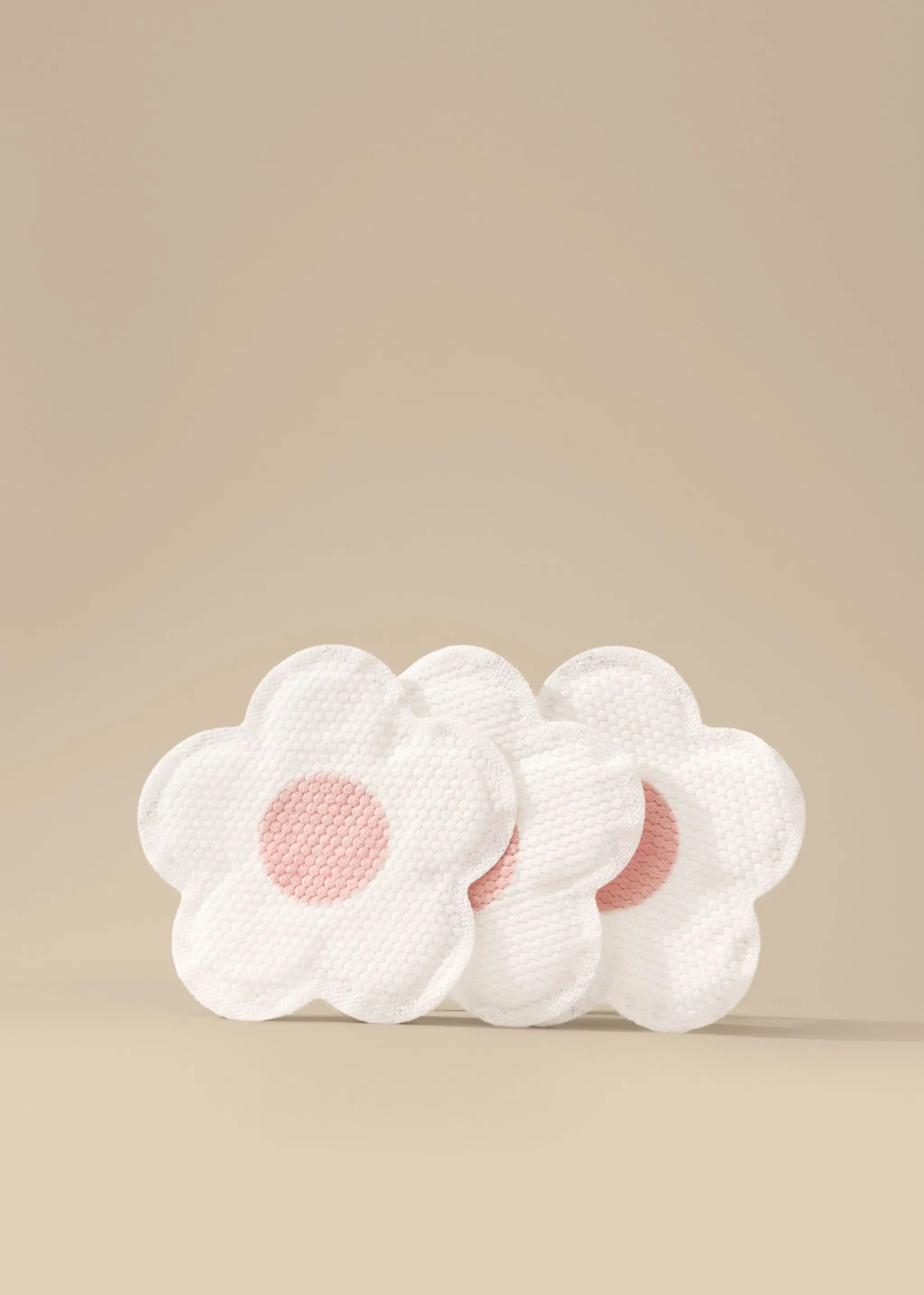 Le Lolo flower-shaped disposable nursing pad with pink centers on a beige background