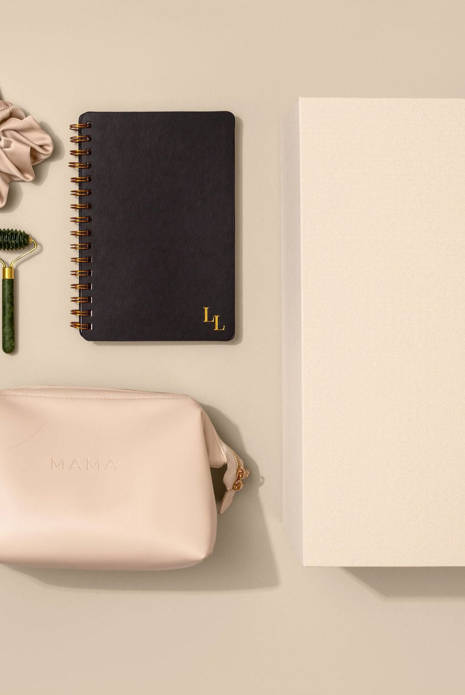 The Every Mama Set by Le Lolo is a collection of items including a 40oz tumbler, satin scrunchie, journal with JOURNAL PROMPTS FOR MAMA + DAILY TRACKER FOR BABY, pure green jade facial roller, 100% organic Beyond Balm, and vegan leather mama carrying bag, packed in a linen memory keepsake box on a beige background