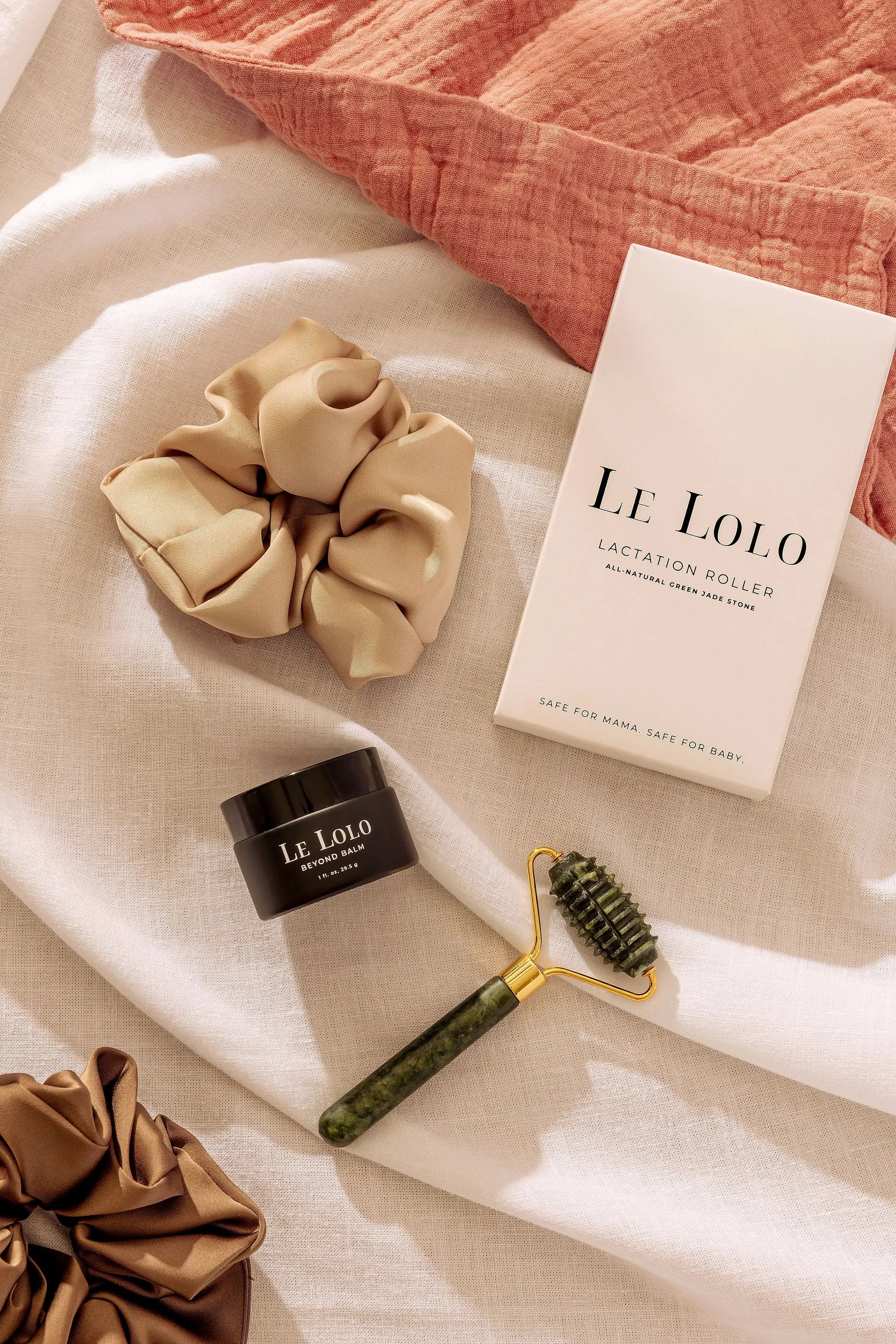 green jade roller for massage, satin scrunchie in beige and brown, and all-natural ointment 